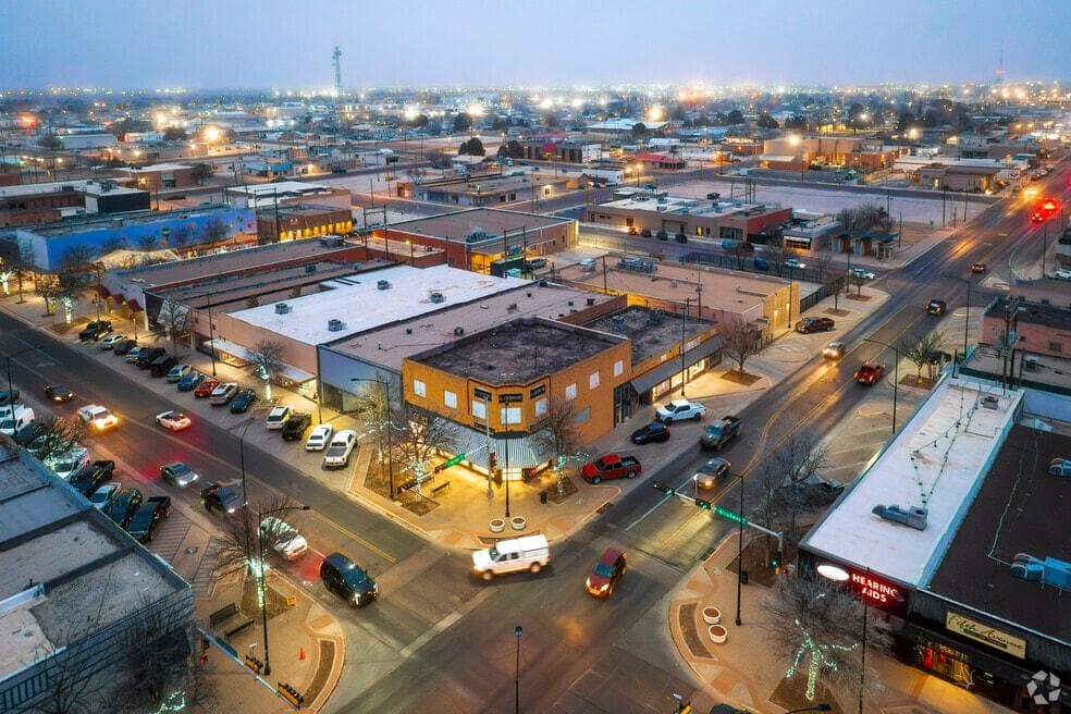 Aerial view of a downtown intersection at dusk with lit streets and shopfronts
